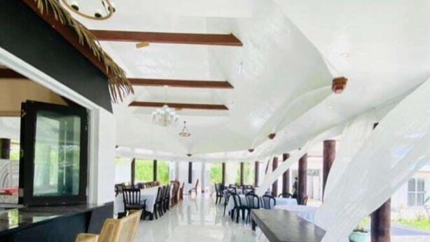 A spacious indoor area with a long counter, multiple tables, and chairs, likely a dining or meeting area. - Maota Hotel (Apia)
