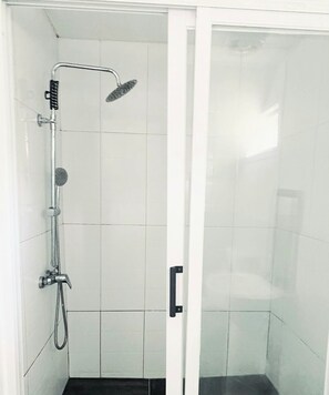 A shower with a handheld showerhead, a wall-mounted faucet, and a handheld scrubber. - Maota Hotel (Apia)