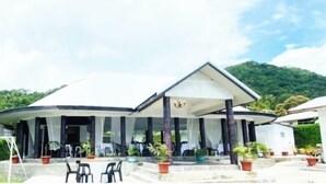 A building with a covered patio area, outdoor seating, and potted plants. - Maota Hotel (Apia)