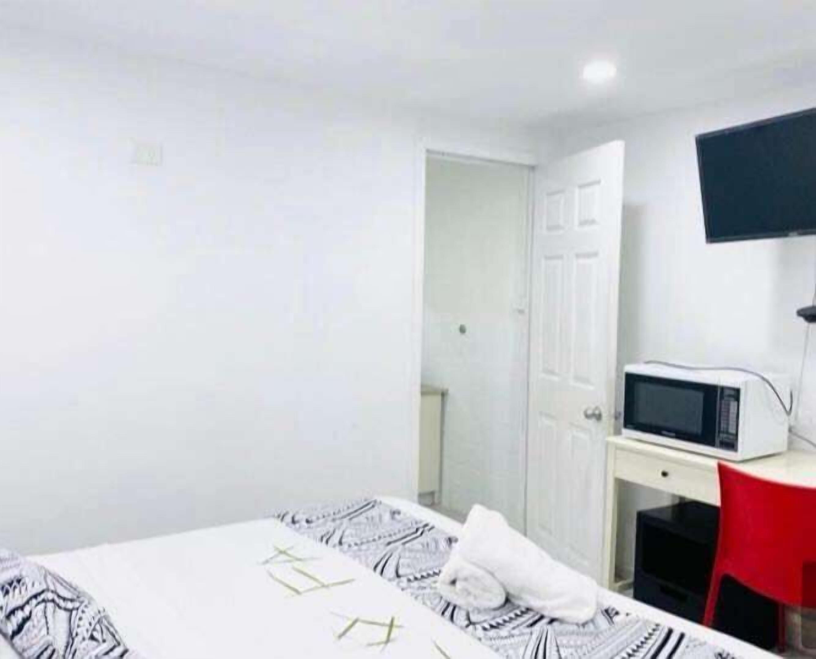 A room with a bed, a desk, a chair, a television, and a door.