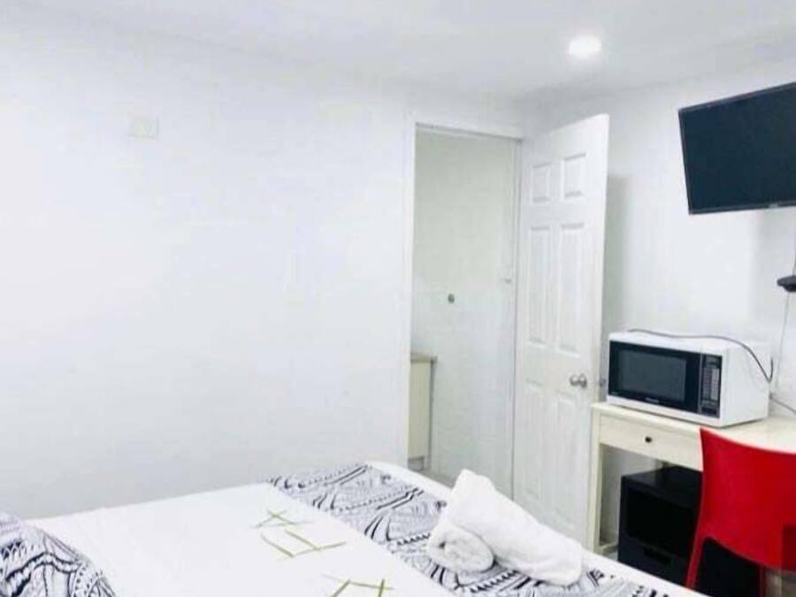 Una habitación con cama, escritorio, silla, televisor y puerta.