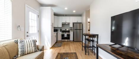 A compact living space with a kitchenette, a sofa, a coffee table, and a TV.