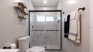 Un bagno moderno con cabina doccia in vetro, un water e un lavandino.