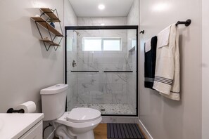 Ein modernes Badezimmer mit einer gläsernen Duschkabine, einer Toilette und einem Waschbecken.