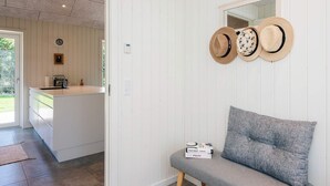 A modern kitchen with a central island, a dining area with a bench, and a wall-mounted hat rack. - 5 Star Holiday Home in Brovst (Brovst)