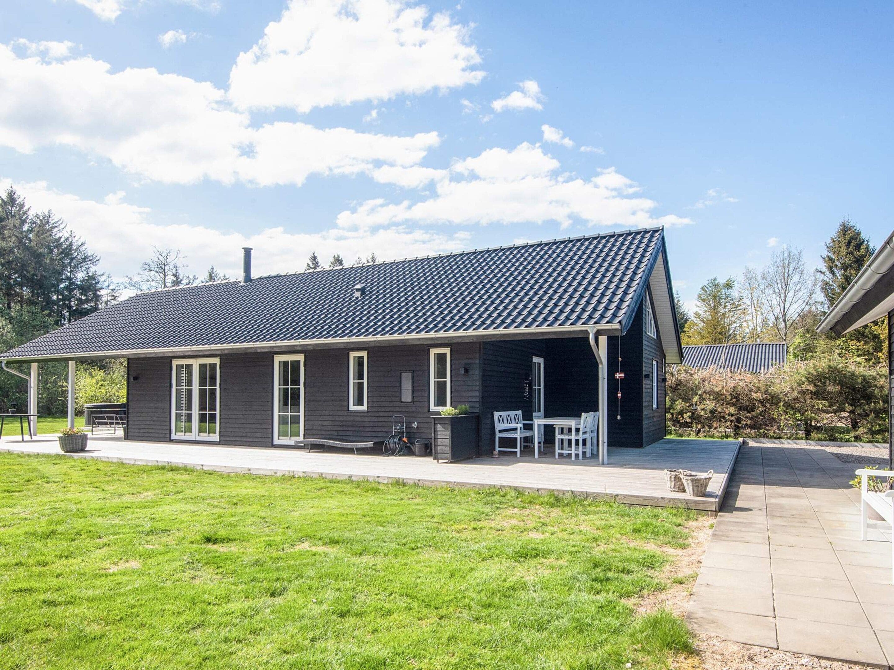Een tweelaags huis met een overdekte patio, een schoorsteen en een verzorgd gazon.