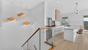 A modern kitchen with a central island, stainless steel appliances, and a glass staircase. - 15A Charteris St, Port Elliot Walk to Horseshoe Bay (Port Elliot)