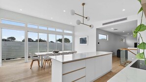 A modern kitchen with large windows, a dining area, and a staircase. - 15A Charteris St, Port Elliot Walk to Horseshoe Bay (Port Elliot)