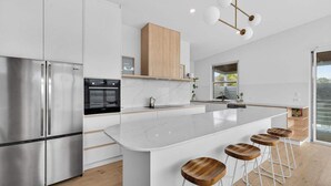 A modern kitchen with a large island, stainless steel appliances, and wooden stools. - 15A Charteris St, Port Elliot Walk to Horseshoe Bay (Port Elliot)