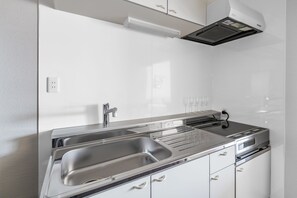 A modern kitchen with stainless steel appliances, a double sink, and white cabinetry. - ASAHIKAWA STAY ECOLE 101  (Asahikawa)
