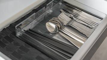 A drawer with neatly organized silverware and a transparent compartment.