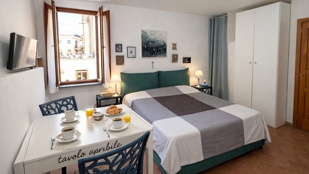 Ein Schlafzimmer mit Bett, einem Frühstückstisch, einem Fernseher und einem Fenster mit Blick.