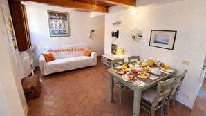 A cozy room with a dining table set for breakfast, a sofa, and a radiator. - La Terrazza a Rio Elba (Rio dell'Elba)