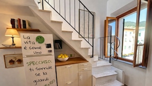 A kitchen with a fridge, a bowl of lemons, and a staircase leading to a balcony. - La Terrazza a Rio Elba (Rio dell'Elba)