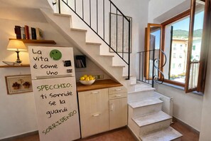 A kitchen with a fridge, a bowl of lemons, and a staircase leading to a balcony. - La Terrazza a Rio Elba (Rio dell'Elba)