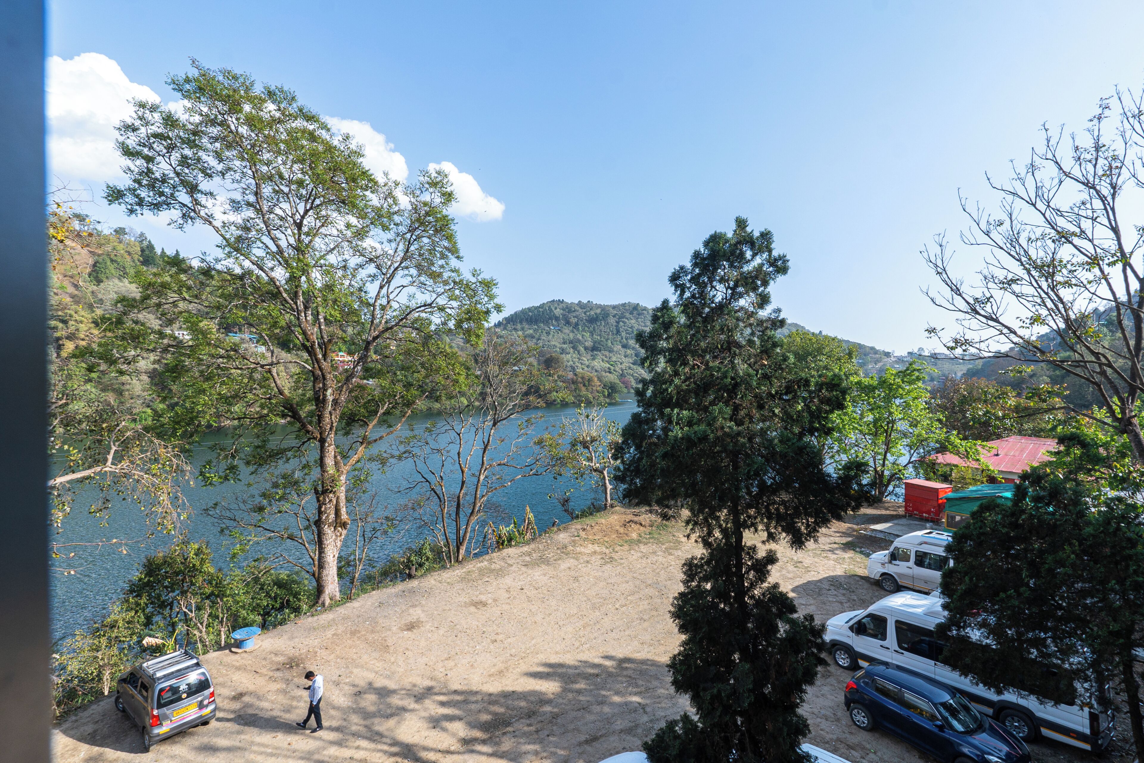 Ein Parkplatz mit Autos, einer Person und Blick auf einen See.