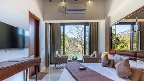 Habitación de hotel moderna con una cama grande, televisión, escritorio y vistas al exterior.