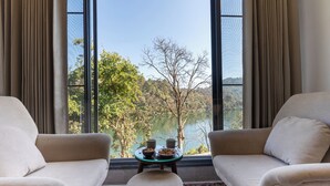 Una habitación con dos sofás orientados hacia un ventanal con vistas a árboles y colinas.