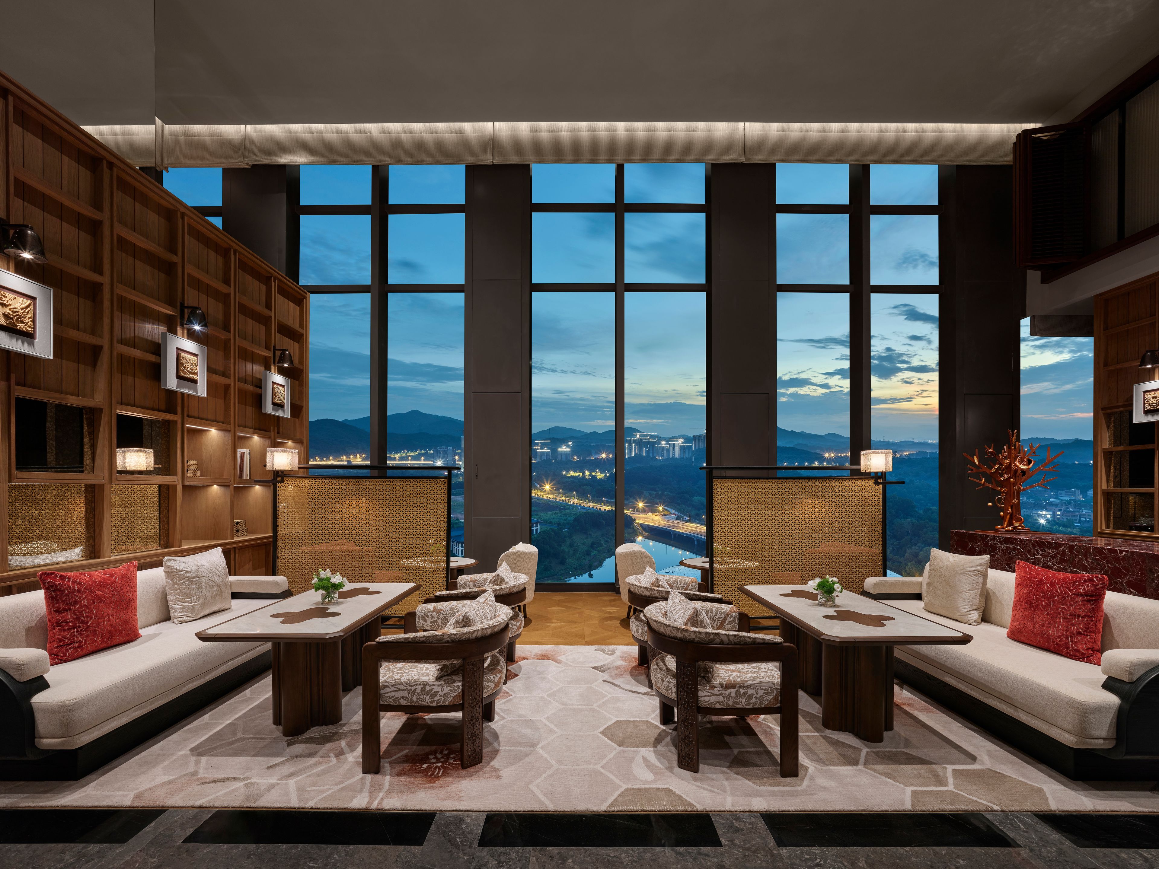 Un salón moderno con vista panorámica de la ciudad, que incluye un sofá, sillas y una mesa de centro.