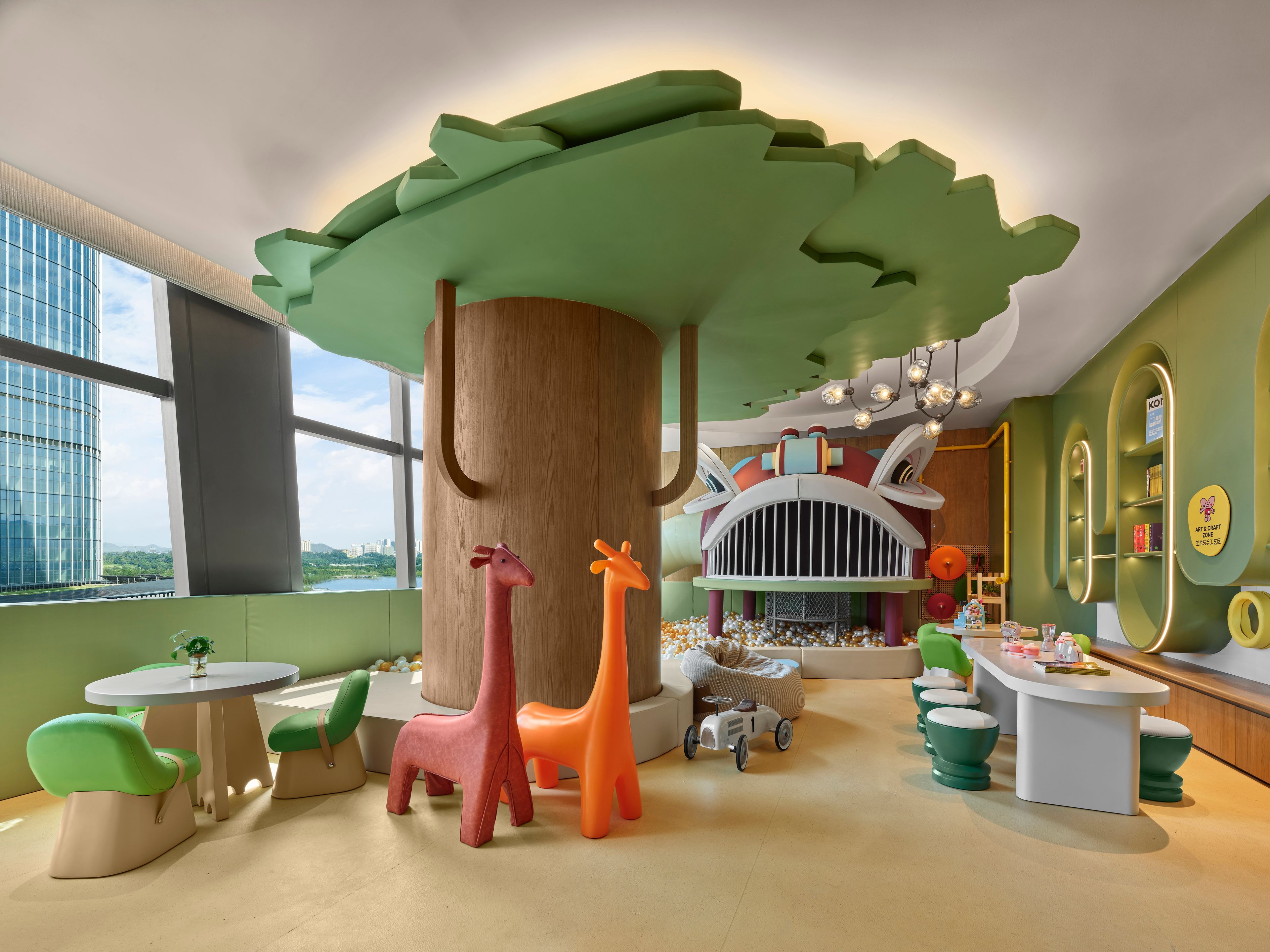 Zona infantil con una gran estructura de árbol, coloridas figuras de animales y una casita.