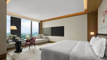Habitación de hotel moderna con una cama grande, un sofá, una mesa de comedor y vistas a la ciudad.