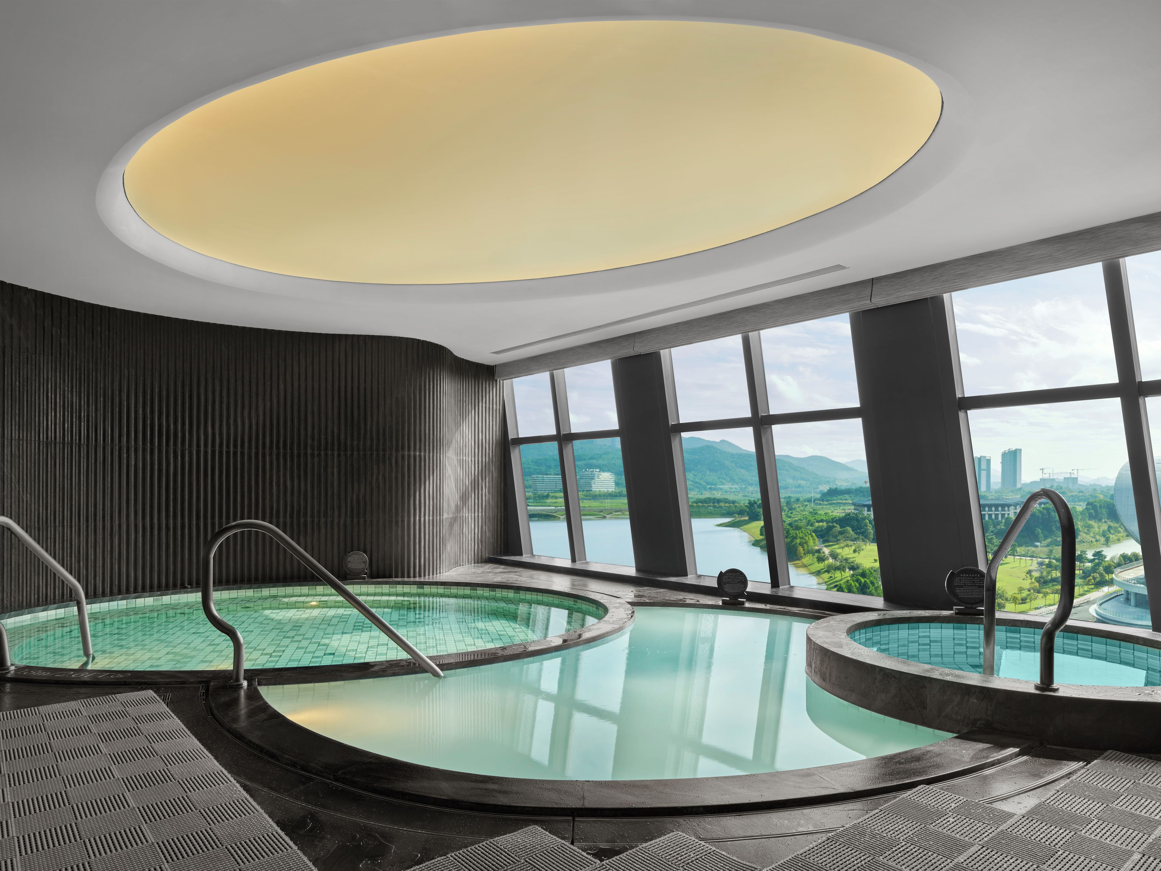 Un área de piscina interior moderna con vistas a la ciudad y a las montañas.