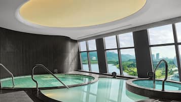 Un área de piscina interior moderna con vistas a la ciudad y a las montañas.
