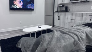 A modern kitchen with a built-in microwave, a refrigerator, and a TV mounted on the wall. - The Suite Spot (Airdrie)