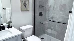 A modern bathroom with a toilet, sink, and shower. - The Suite Spot (Airdrie)