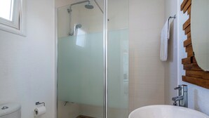 A bathroom with a glass shower enclosure, a white sink, and a wooden-framed mirror. - Seawaves 1- BR Apt. by Meneou Beach (Meneou)