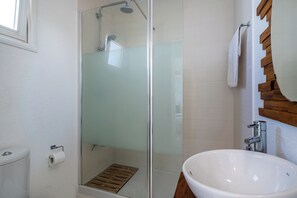 A bathroom with a glass shower enclosure, a white sink, and a wooden-framed mirror. - Seawaves 1- BR Apt. by Meneou Beach (Meneou)