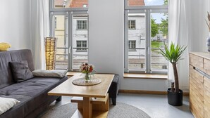 Un salon moderne avec un canapé, une table en bois et une plante en pot.