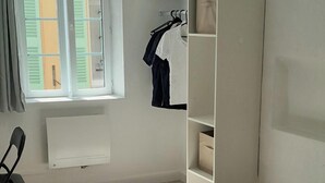 Una camera da letto con un letto, un armadio, una sedia e una finestra con persiane.