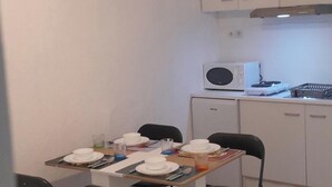 Una piccola cucina pulita con mobili bianchi, un forno a microonde e un tavolo da pranzo per quattro persone.