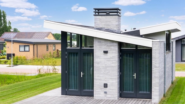 Una casa moderna con techo plano, amplias ventanas y una terraza de madera.