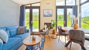 Una sala de estar moderna con un sofá azul, una mesa de centro redonda y un comedor con sillas y una mesa.