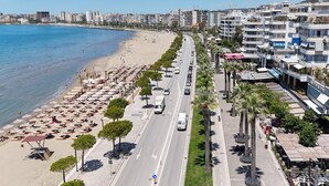 A coastal road with beachside seating, a clear sky, and modern buildings. - Lunara Apartment (Vlorë)