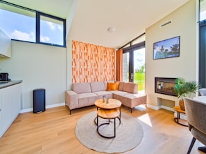 Una sala de estar moderna con un sofá seccional, una mesa de centro redonda de madera y vistas al exterior.
