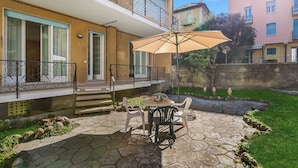 A patio with a table, chairs, and an umbrella. - Casa Adelina, Center Flat With Private Garden (Stresa)