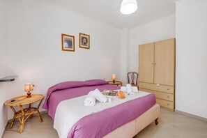 Ein Schlafzimmer mit zwei Betten, einem Kleiderschrank, einem Nachttisch mit Lampe und zwei gerahmten Bildern an der Wand.