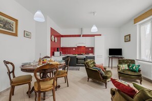 Een moderne woonkamer met een eethoek, keuken en een televisie.