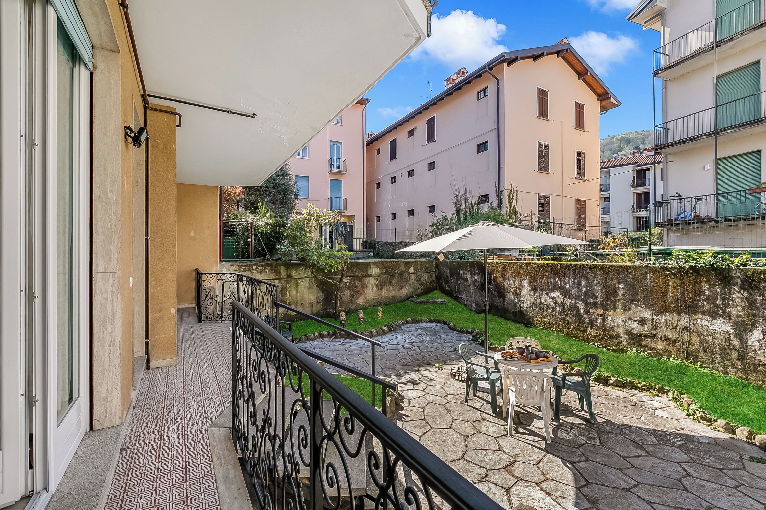 Ein Balkon mit Steinterrasse, Gartenmöbeln und Blick auf benachbarte Gebäude.