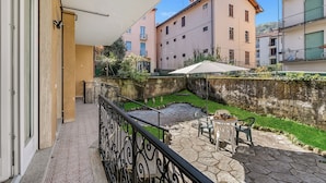 A balcony with a stone patio, outdoor furniture, and a view of neighboring buildings. - Casa Adelina, Center Flat With Private Garden (Stresa)