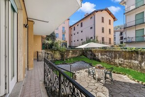 Un balcon avec une terrasse en pierre, du mobilier d’extérieur et une vue sur les bâtiments voisins.