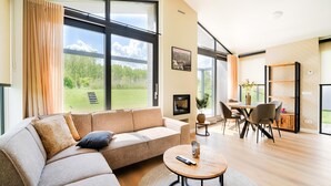 Ein modernes Wohnzimmer mit einem Ecksofa, einem runden Couchtisch und einem Essbereich mit Tisch und Stühlen.
