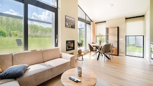 Ein geräumiges Wohnzimmer mit großem Fenster, einer Couch, einem Couchtisch und einem Essbereich.