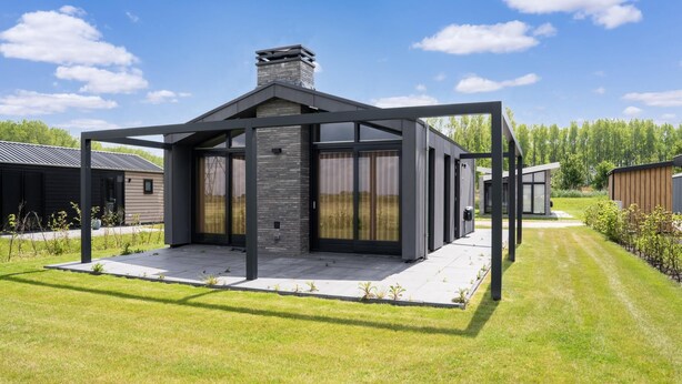 Une maison moderne dotée d’un patio couvert, d’une cheminée et d’une pelouse bien entretenue.