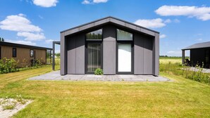 Un bâtiment moderne doté d’un toit plat, de grandes fenêtres et d’une pelouse verdoyante.
