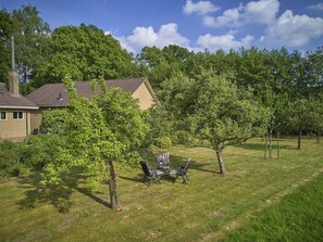 Un immobile residenziale con una casa, un prato e un piccolo angolo relax con sedie e tavolo.