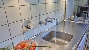 A kitchen with a stainless steel sink, a small dish rack, and a bowl of fruit. - Rural holiday home with expansive views (Aalten)